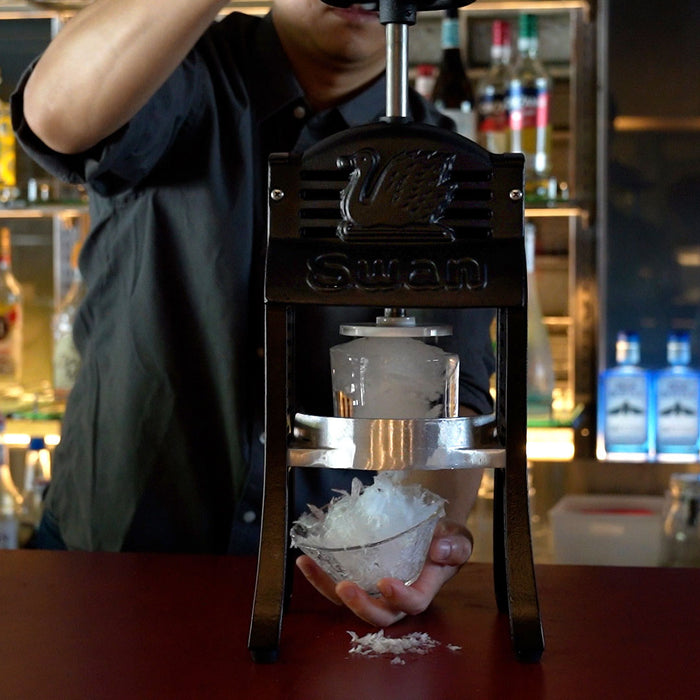Black Swan Cast Iron Manual Ice Shaver in use in the bar counter